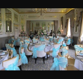 Aqua Organza Bows tied to the side on Gold Chairs provided by venue