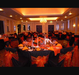 Black Chair Covers and Table Linen with Orange Organza Bows and Pin-tuck Table Runners