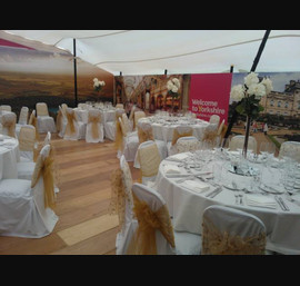 Gold embroidered organza and gold sashes on white chair covers. The Welcome to Yorkshire VIP marquee at the Great Yorkshire Show