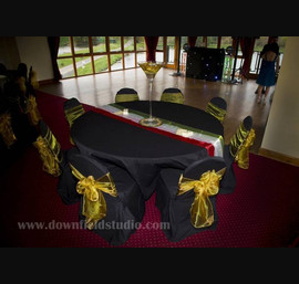 Gold single bow on black chair cover with white, red and green table runner on black table cloth at Forbes of Kingennie
