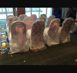 Pink floral veil alternated with baby pink bows on white chair covers