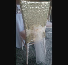 Gold sequin cap with organza bow on chiavari chair