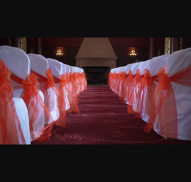 White Chair Covers and Bright Orange bows at Doxford Hall