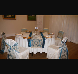 Peacock blue and gold flock sashes on white chair covers at Doxford Hall