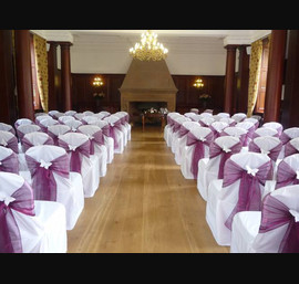 Wine organza sashes on white chair covers at Doxford Hall