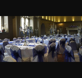 White Chair Covers with Midnight blue bows. Flowers by Secret Garden at Ellingham Hall