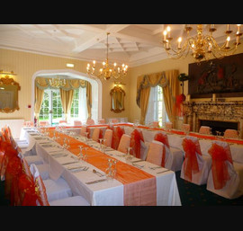 White Chair Covers and Bright Orange Bows at Otterburn Towers