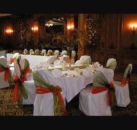 White Chair Covers with green and orange double bows tied on the side at The White Swan
