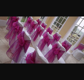 White chair covers with bright pink bow at Woodhill Hall