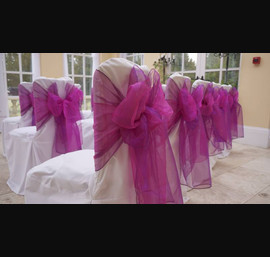 White chair covers with bright pink bow at Woodhill Hall