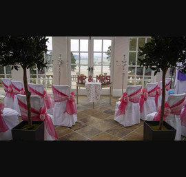 White chair covers with raspberry and lace side bows at Woodhill Hall