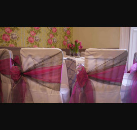 White chair covers with silver and pink side bows at Woodhill Hall