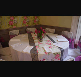White chair covers with silver & pink bows with a floral runner & silver pin tuck runner at Woodhill Hall